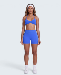 Modelo veste conjunto desportivo azul VD Beyond Limits com top halter e calções de cintura alta em tecido seamless.