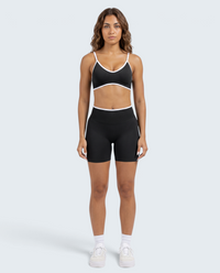 Modelo veste conjunto desportivo seamless preto VD Beyond Limits com top cropped e calções canelados de cintura alta.