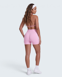 Modelo veste conjunto desportivo rosa VD Beyond Limits com top halter e calções seamless de cintura alta