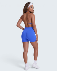 Modelo veste conjunto desportivo azul VD Beyond Limits com top halter e calções seamless de cintura alta