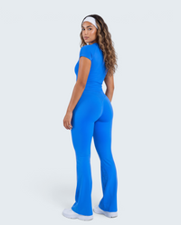 Modelo veste conjunto VD Beyond Limits azul de t-shirt justa e calças flare de cintura alta em fundo neutro