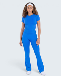 Modelo veste conjunto azul VD Beyond Limits com t-shirt justa e calças flare de cintura alta para desporto