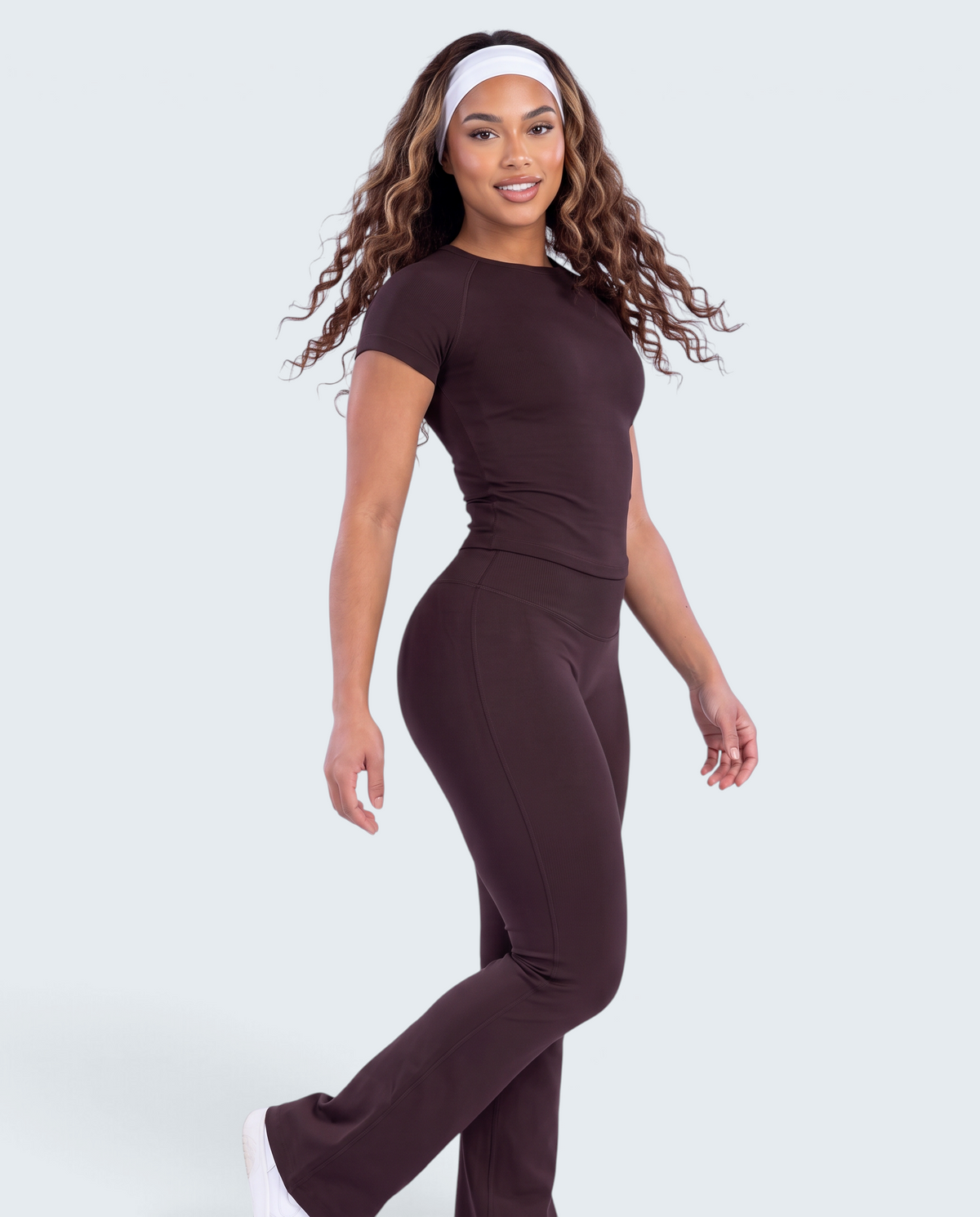 Modelo veste conjunto castanho VD Beyond Limits com t-shirt justa e calças flare de cintura alta em tecido elástico