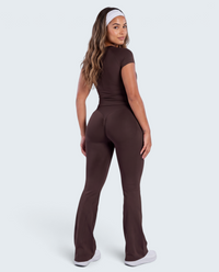 Modelo veste conjunto castanho VD Beyond Limits com t-shirt justa e calças flare de cintura alta para desporto.