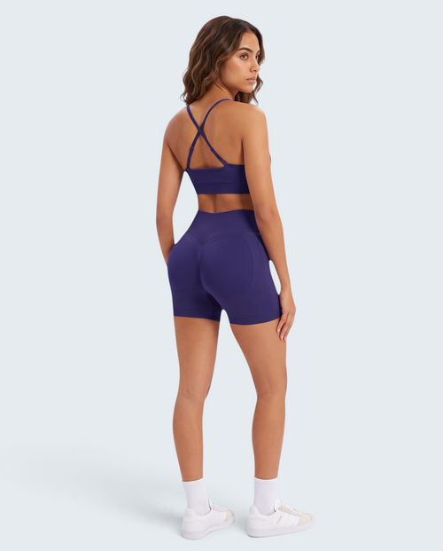 Modelo veste conjunto desportivo roxo escuro VD Beyond Limits com top de alças cruzadas e calções seamless