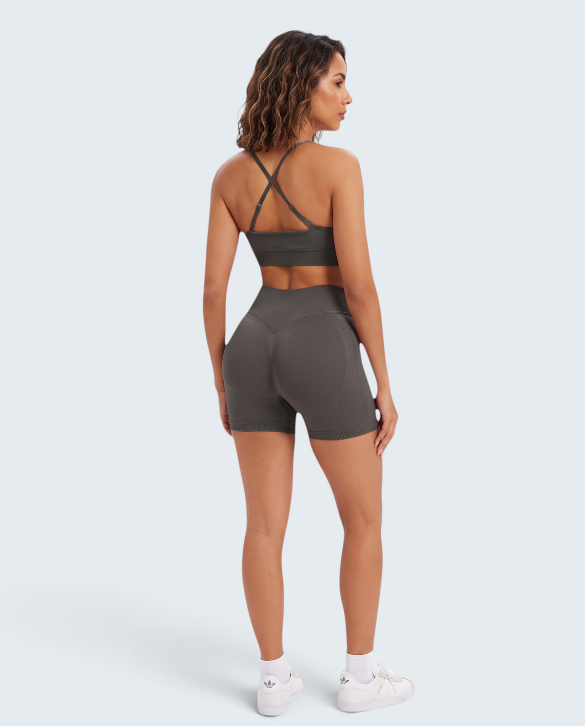 Modelo de costas veste conjunto seamless cinza VD Beyond Limits com top de alças cruzadas e calções de cintura subida