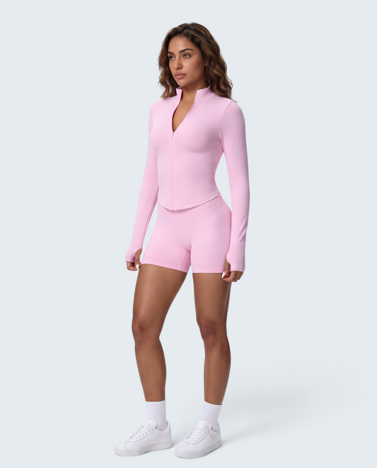 Modelo veste conjunto rosa VD Beyond Limits com casaco de fecho e calções seamless de cintura subida para treino.