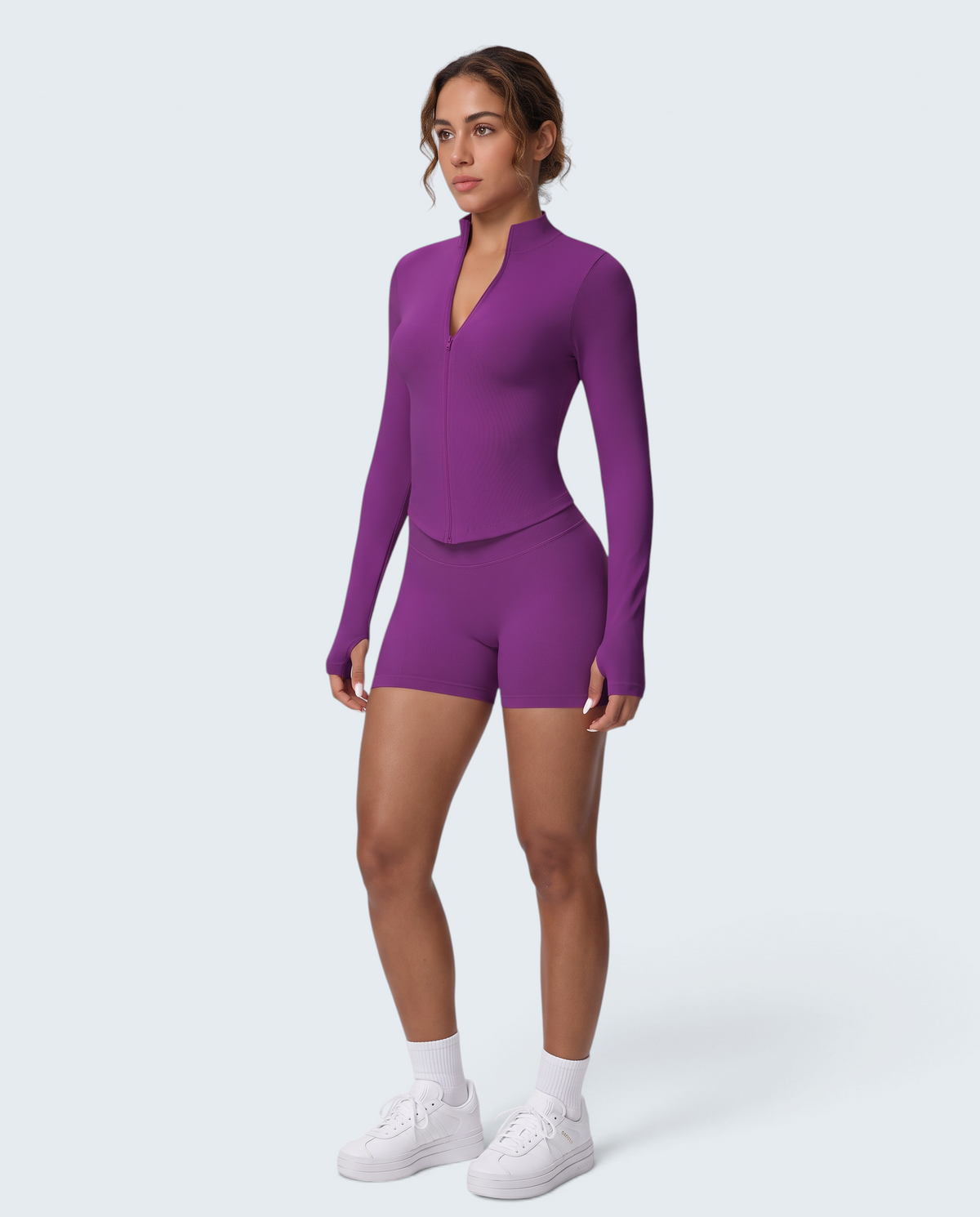 Modelo veste conjunto desportivo roxo VD Beyond Limits com casaco de fecho e calções seamless de cintura subida.
