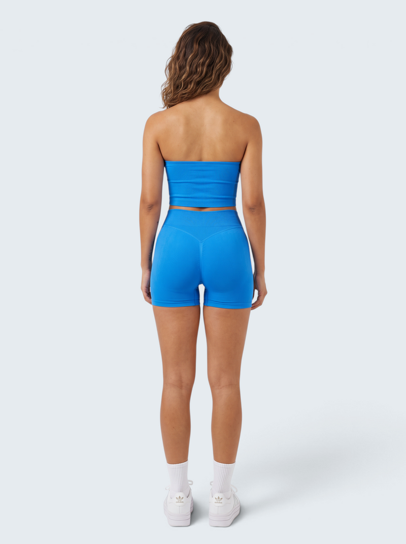 Mulher de costas vestindo conjunto desportivo azul VD Beyond Limits com top cropped e calções seamless modeladores