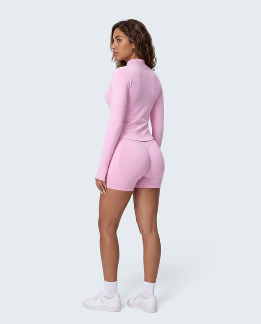 Modelo veste conjunto seamless rosa VD Beyond Limits com casaco de fecho e calções de cintura subida, vista traseira.