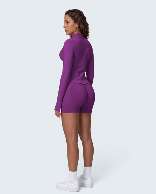 Modelo veste conjunto desportivo roxo VD Beyond Limits com casaco de fecho e calções seamless de cintura subida