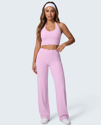 Modelo veste conjunto desportivo rosa VD Beyond Limits com top halter seamless e calças wide leg de cintura alta.