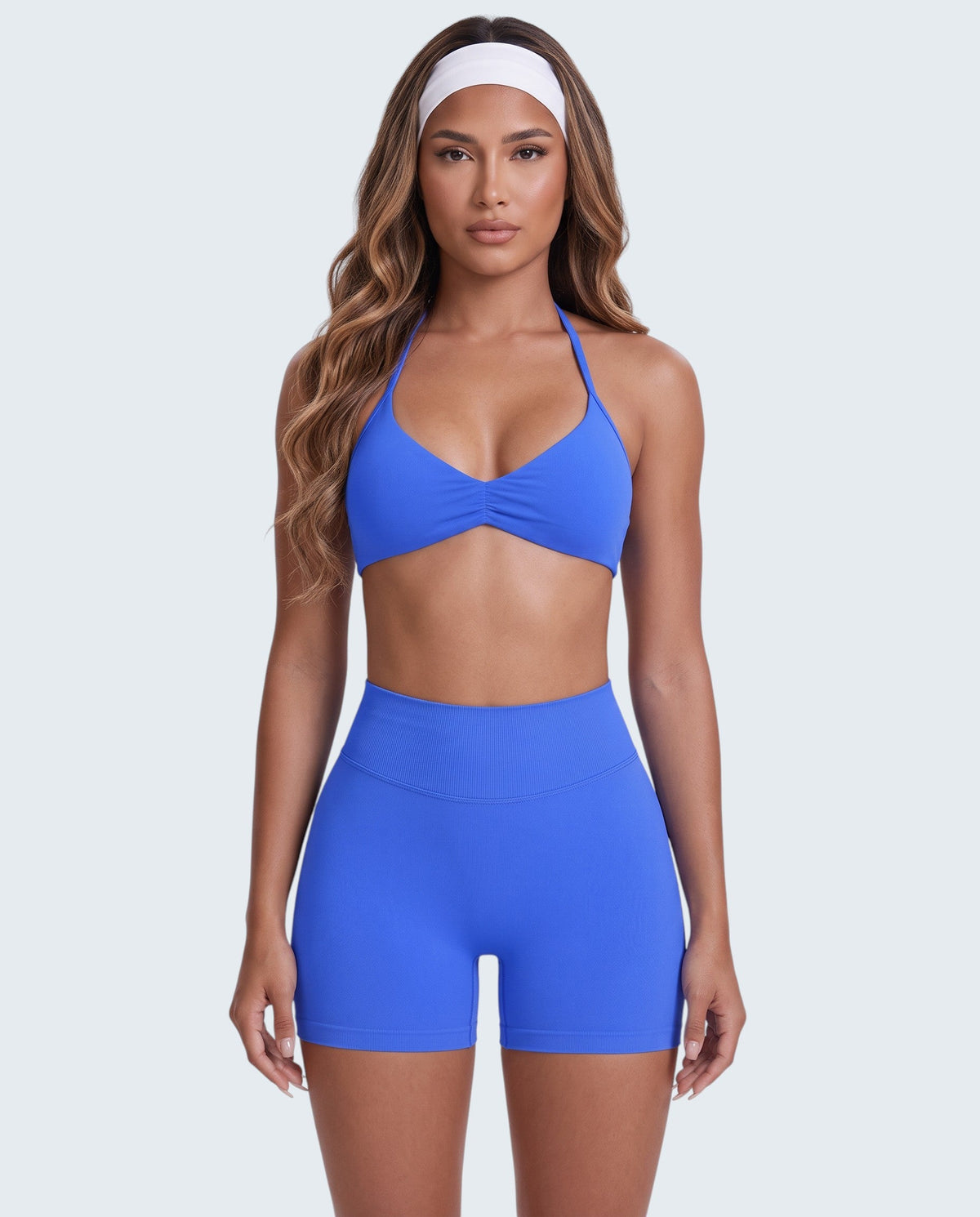 Modelo veste conjunto desportivo azul VD Beyond Limits com top halter e calções de cintura alta em tecido seamless.