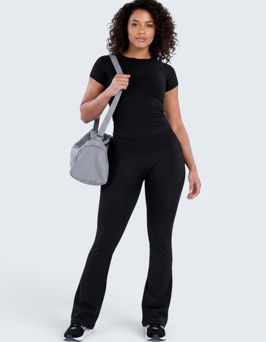 Modelo veste conjunto desportivo preto VD Beyond Limits com t-shirt justa e calças flare de cintura alta.