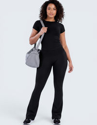 Modelo veste conjunto desportivo preto VD Beyond Limits com t-shirt justa e calças flare de cintura alta.