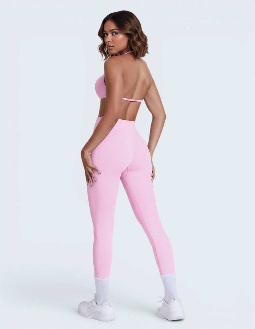 Modelo veste conjunto desportivo rosa VD Beyond Limits com top e calções seamless de cintura alta em fundo neutro
