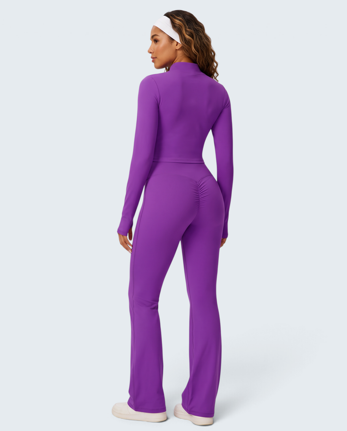Modelo de costas veste conjunto VD Beyond Limits roxo de malha soft com casaco, top e calças flare de cintura subida.