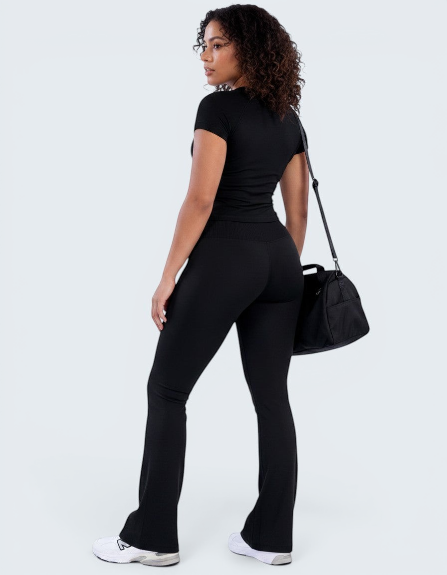 Modelo veste conjunto preto VD Beyond Limits com t-shirt justa e calças flare de cintura alta, estilo athleisure.