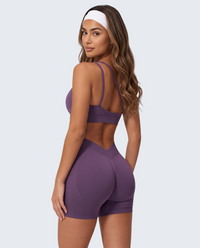Modelo veste conjunto seamless roxo escuro VD Beyond Limits com top e calções de cintura subida para treino