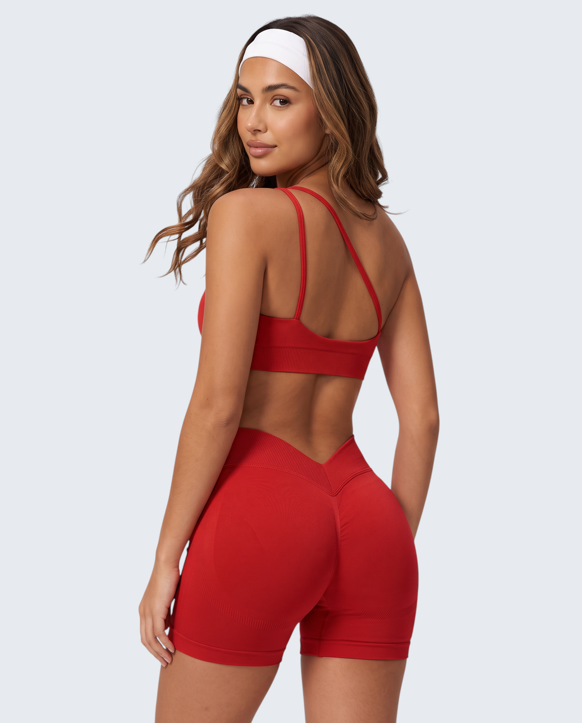 Modelo veste conjunto desportivo vermelho VD Beyond Limits com top e calções seamless de cintura subida e efeito push-up