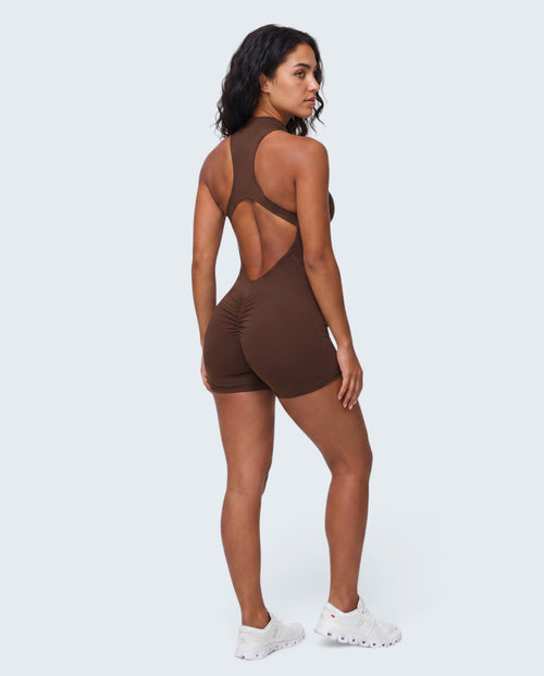 Modelo veste macacão curto castanho Seamless Sculpt da VD Beyond Limits com costas abertas e detalhe franzido