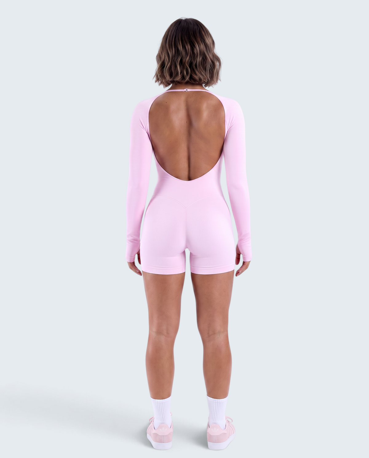 Vista traseira de modelo usando macacão curto rosa VD Beyond Limits seamless de manga comprida com costas abertas