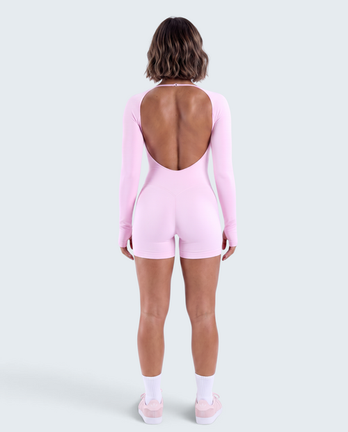 Vista traseira de modelo usando macacão curto rosa VD Beyond Limits seamless de manga comprida com costas abertas