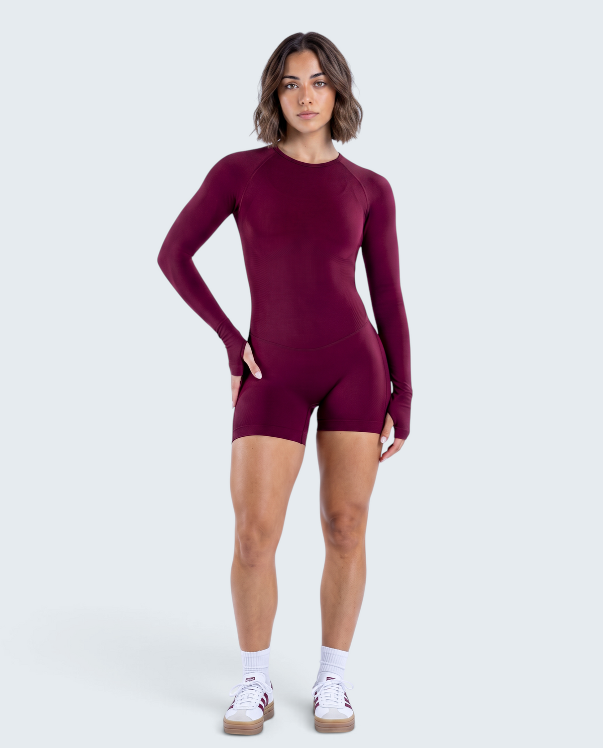 Modelo veste macacão curto bordô VD Beyond Limits seamless de manga comprida, ideal para yoga e treino funcional.