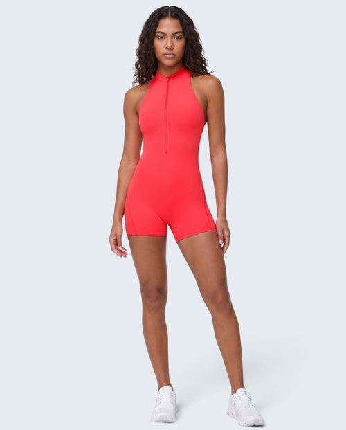 Modelo veste macacão desportivo vermelho VD Beyond Limits com fecho frontal, tecido seamless e corte curto.